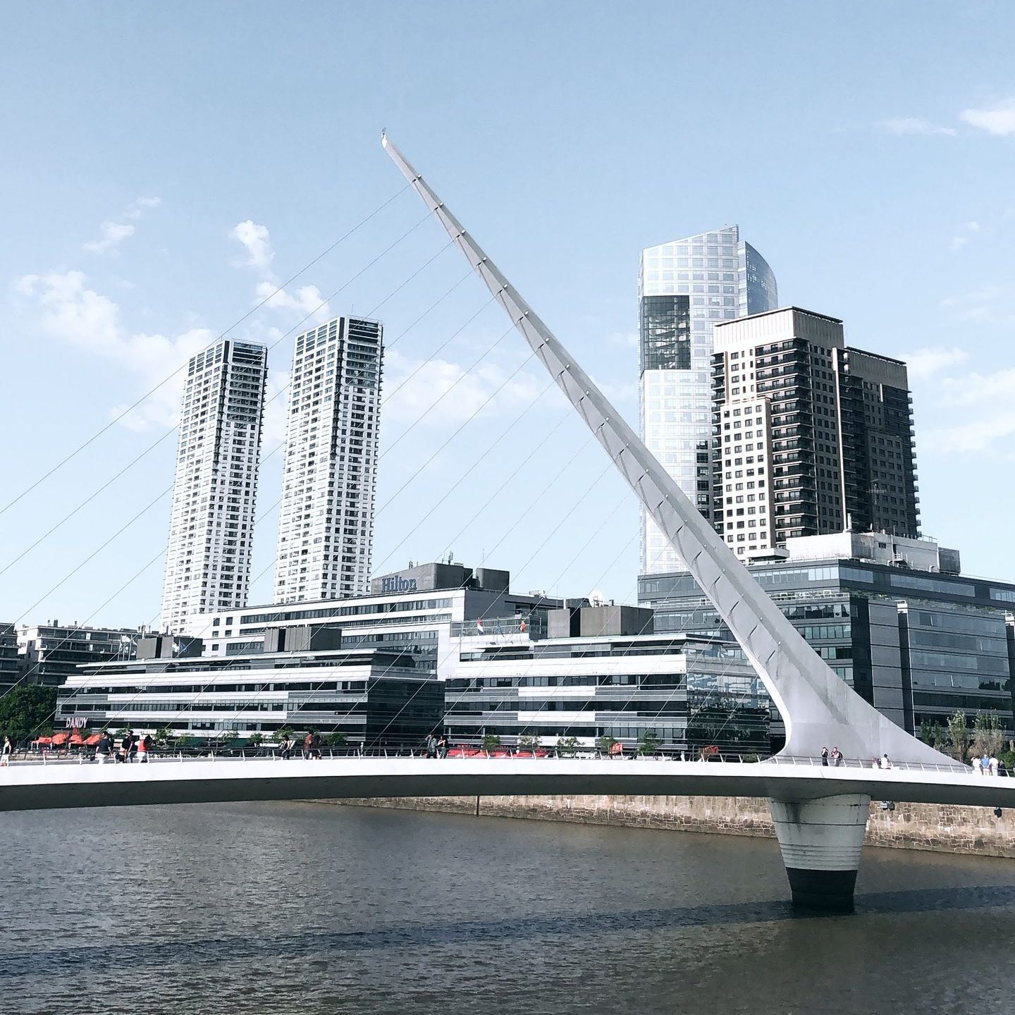 Futuristic Puente de la Mujer bridge in Buenos Aires over water with modern cityscape.